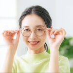 メガネを両手で押さえる女性