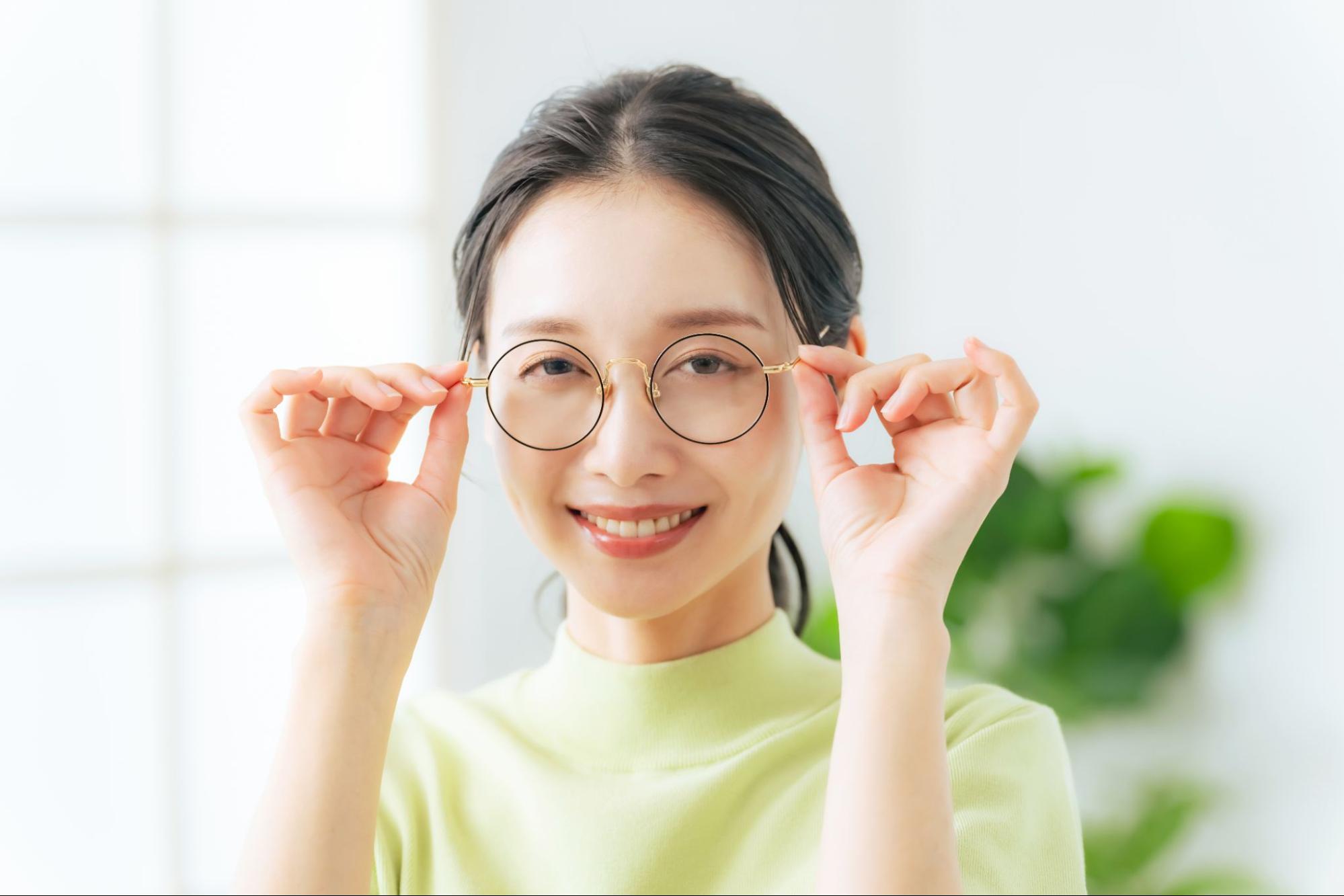 メガネを両手で押さえる女性
