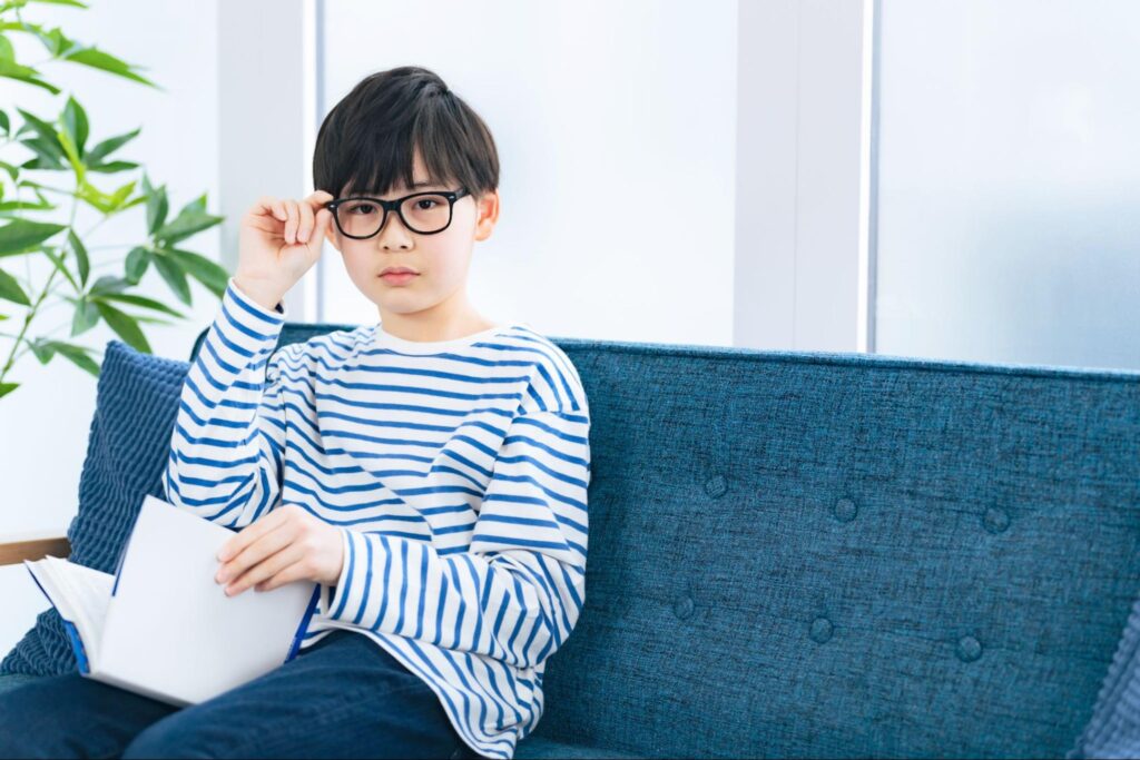 メガネを片手で押さえる男の子