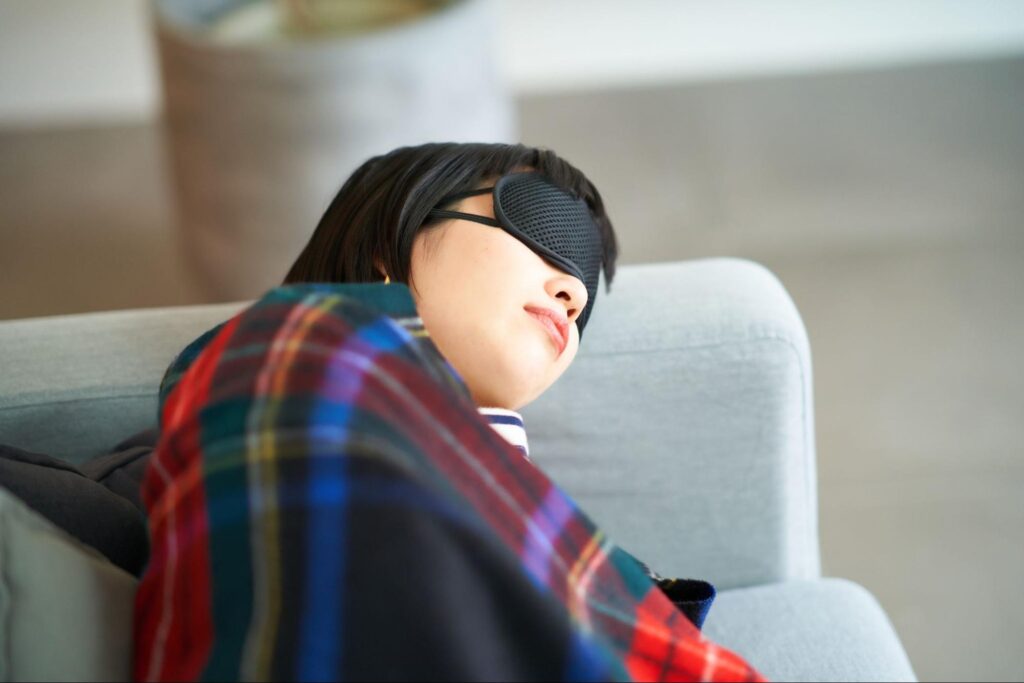 ドライアイによる頭痛を予防するためにアイマスクをつけて目を休ませている女性