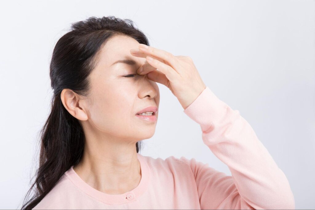 ドライアイで目を押さえる更年期の女性