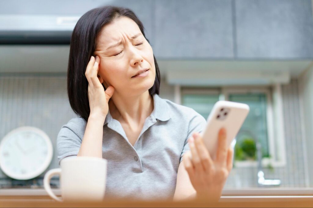 スマホを見ているときにドライアイになりつらそうにしている女性