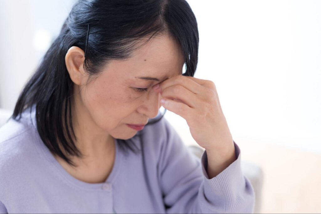 ドライアイがつらく目を押さえる更年期の女性